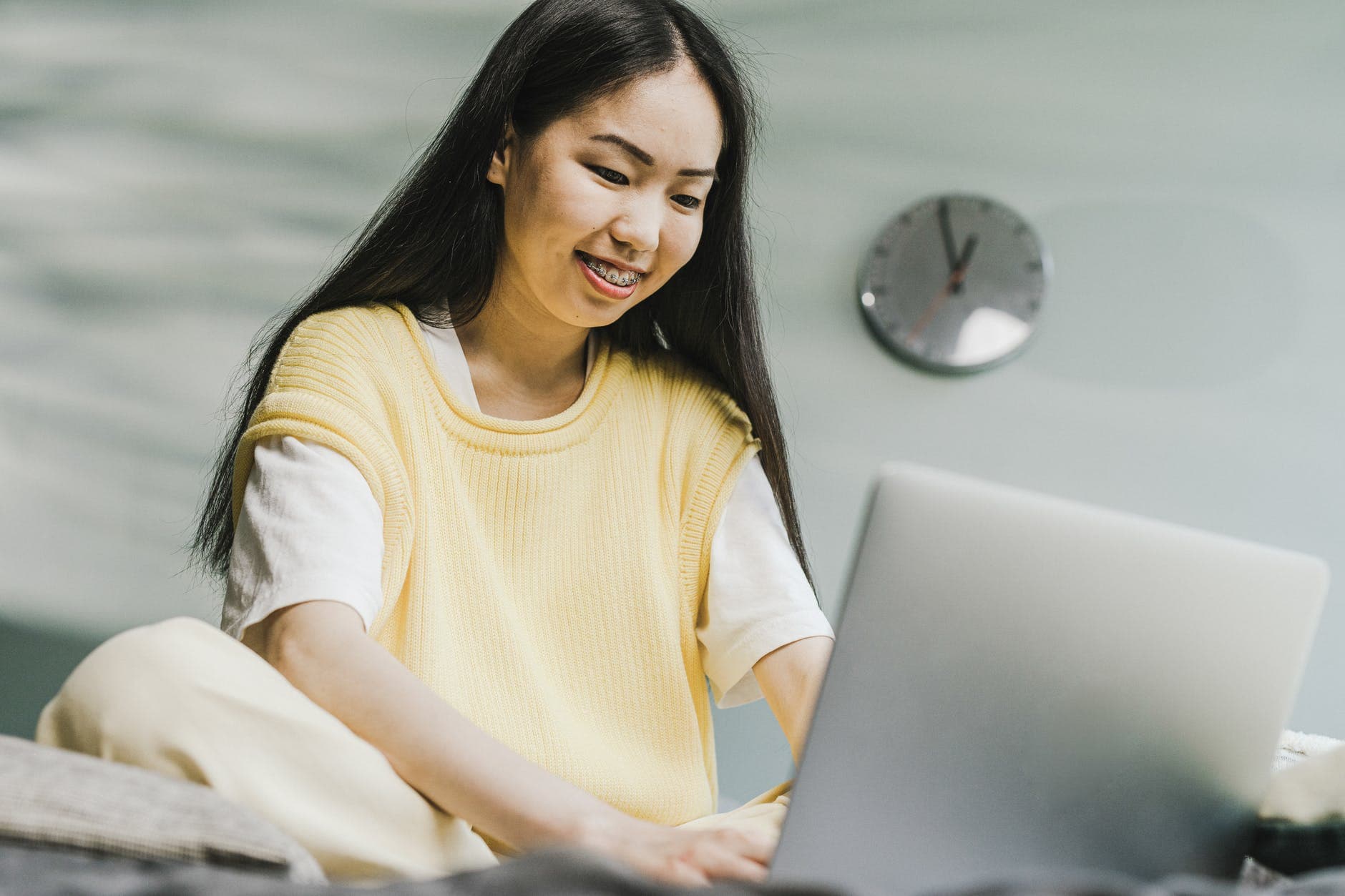 Estudante sorridente usando um notebook sentada no chão