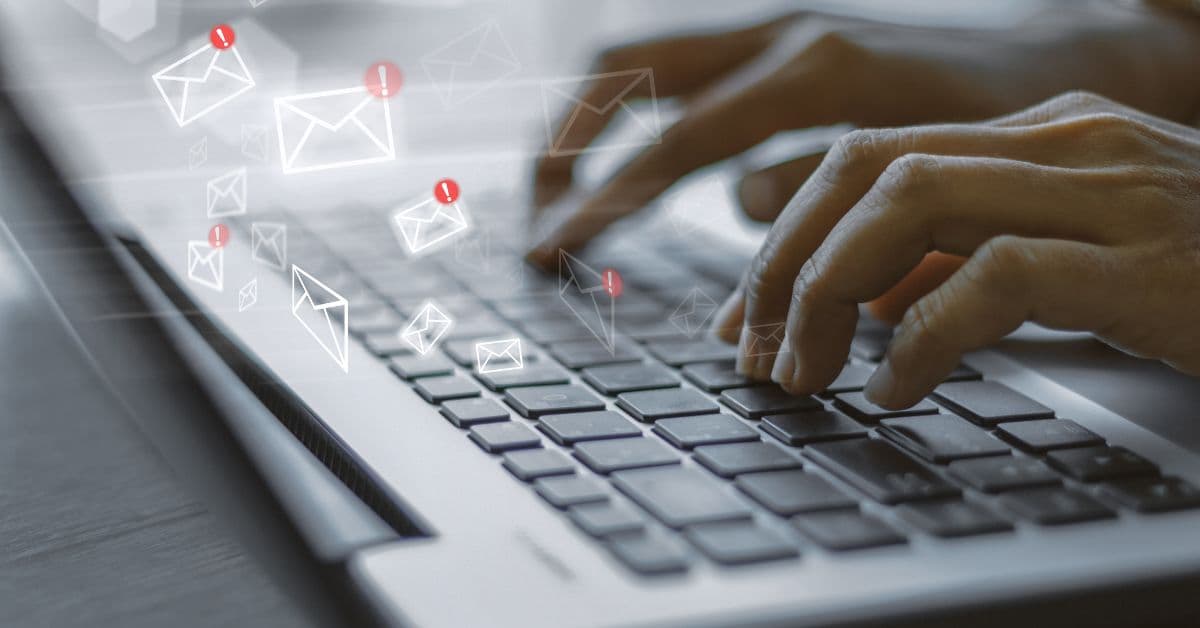 Mãos digitando em um notebook com ícones de e-mail flutuando