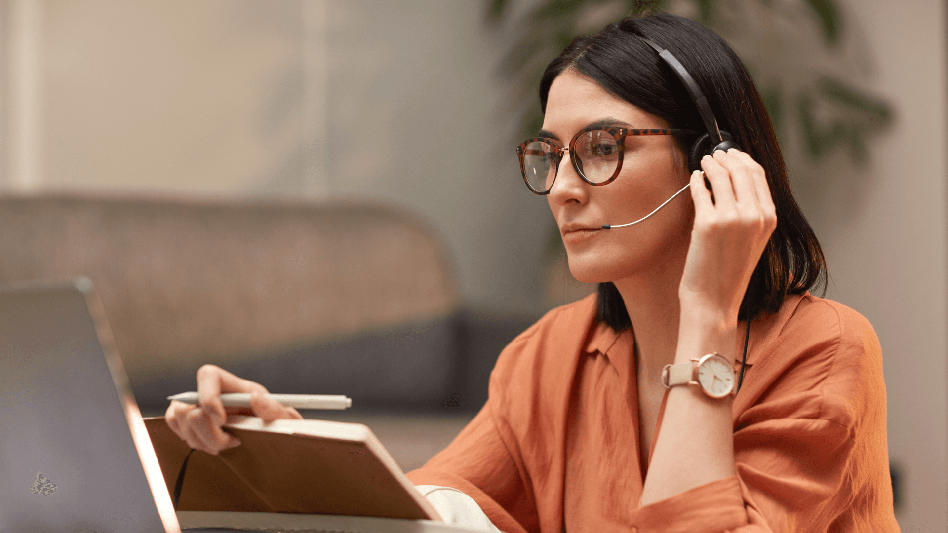 Professora com fone de ouvido e caderno durante uma aula online