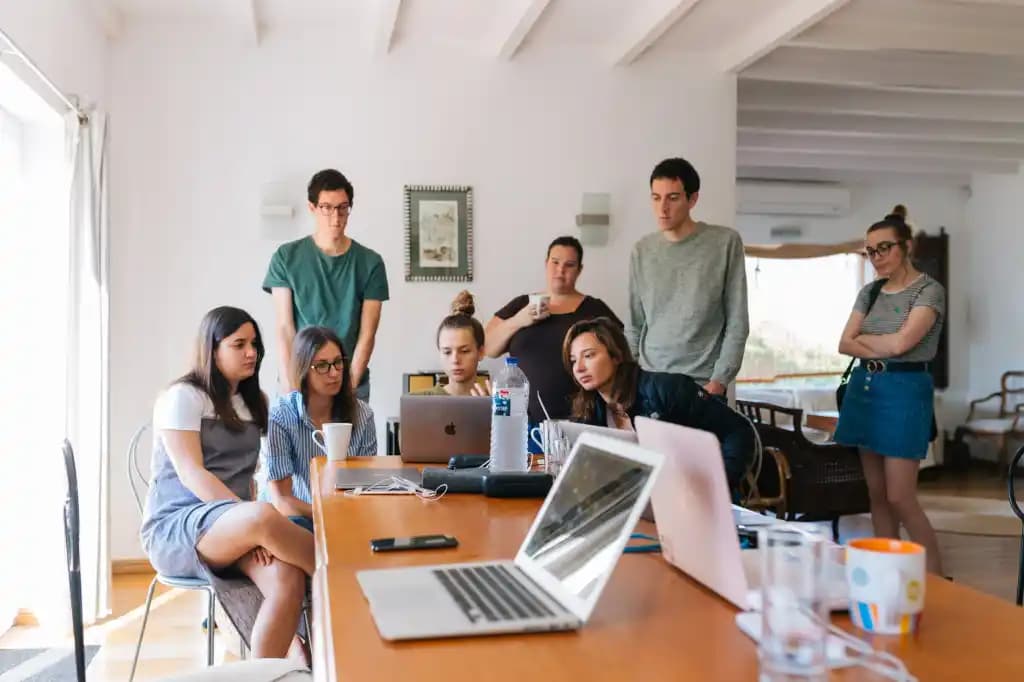 Equipe jovem reunida em volta de uma mesa com notebooks, trabalhando em conjunto